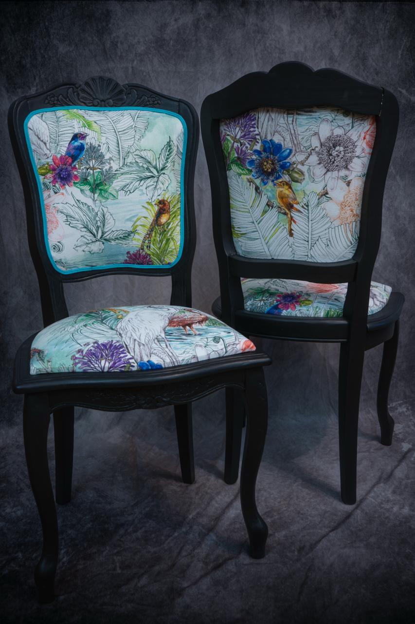 chaise peinte en noir avec du tissu à motif d'oiseaux 
        et de fleurs colorés, finition galon bleu et orange