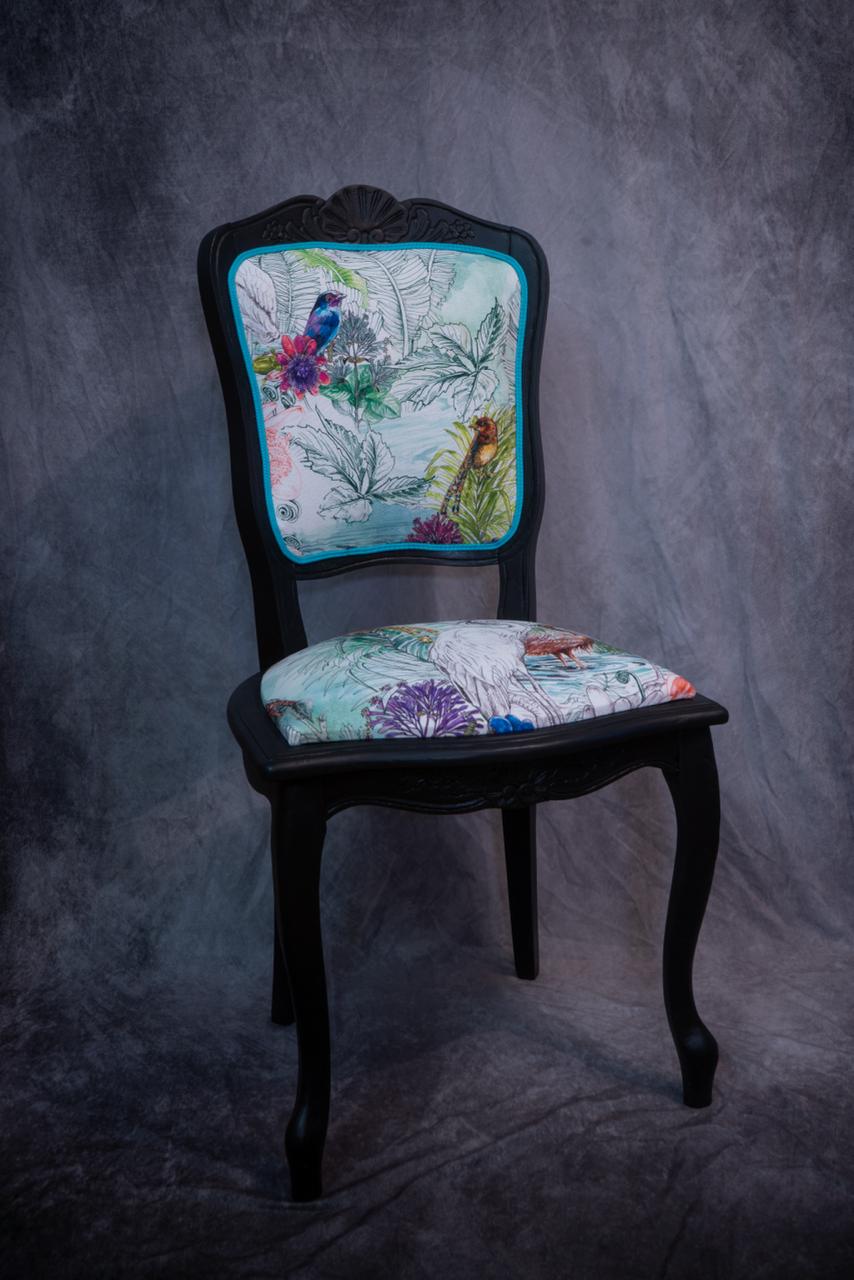 chaise peinte en noir avec du tissu à motifs 
            d'oiseaux colorés, finition galon bleu clair